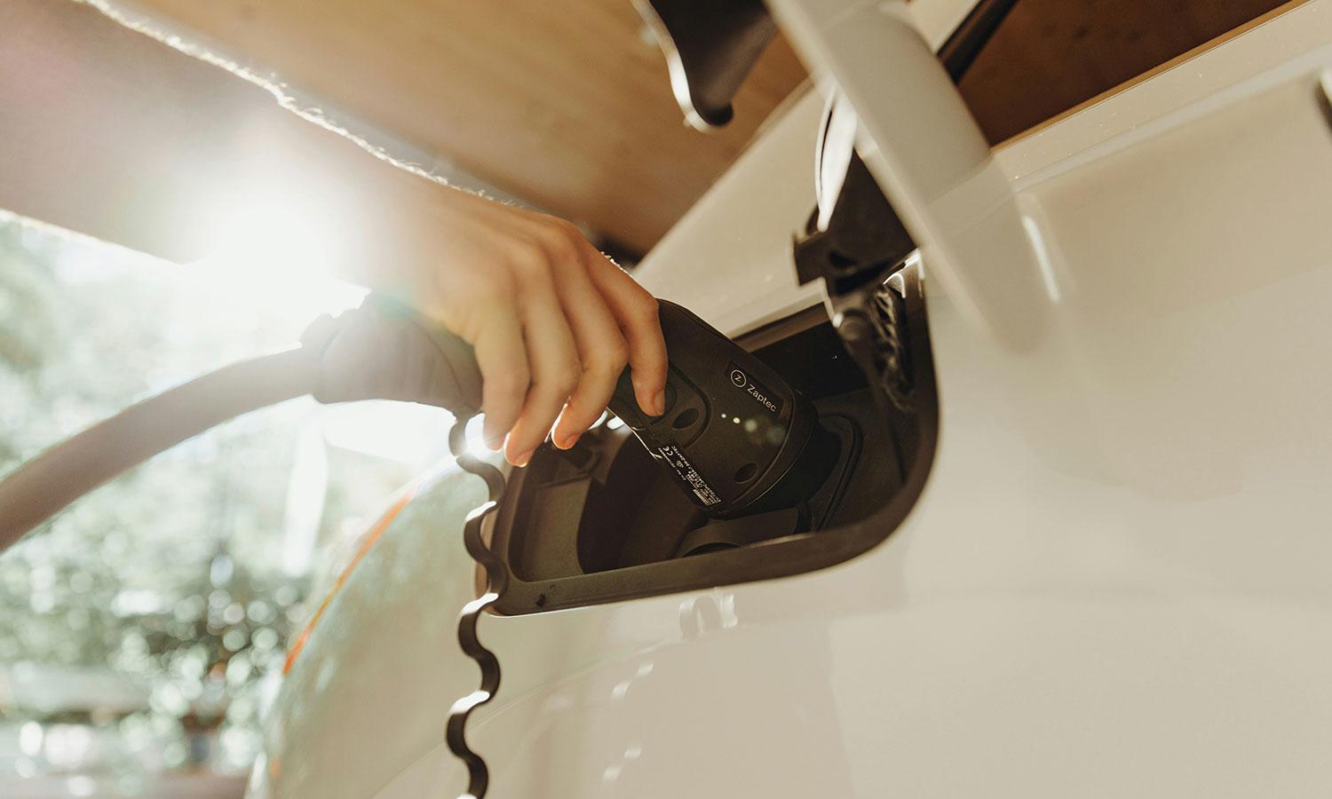 Una persona que recarga un auto eléctrico blanco