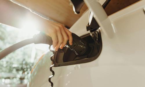 Una persona que recarga un auto eléctrico blanco